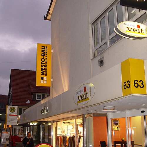 Ausstecktransparent Aluminium, Motiv Westo Bau extern mit Strahlern angeleuchtet