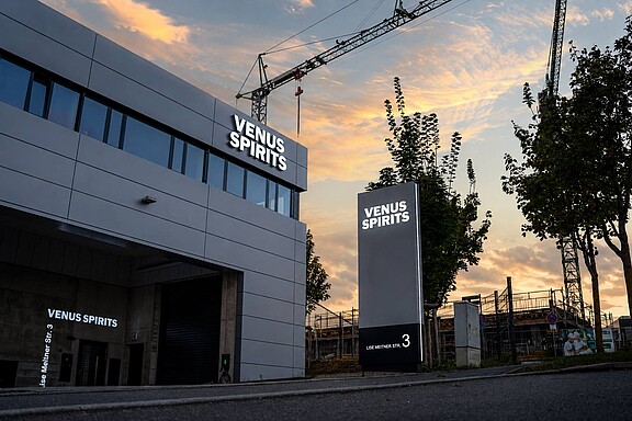 Werbeanlage für Venus Spirit mit beleuchtetem Fassadenlogo und Werbepylon