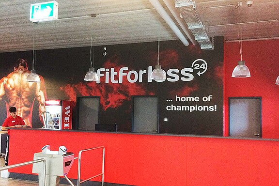 Wandbeschriftung mit bedruckten Designfolien in Firmen CI - Fit for less